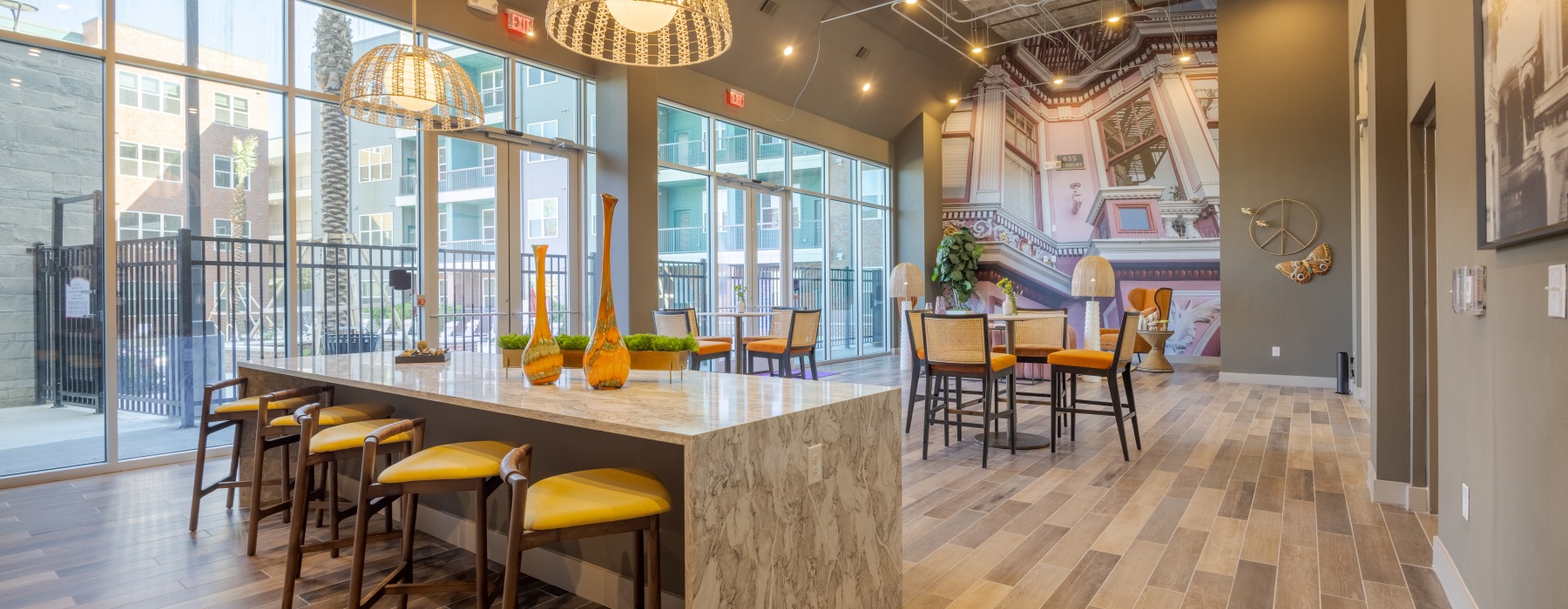 A well lit resident lounge with pocket seating, colorful mural and view outside