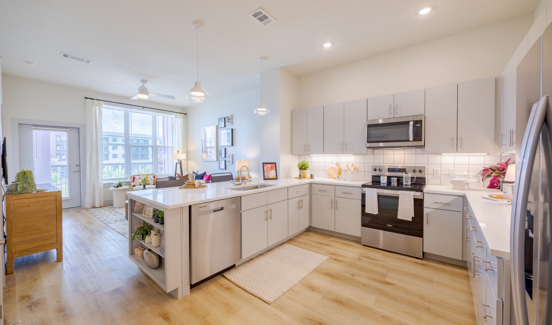 White kitchen with island and bar seating at The Janis North Austin apartments in TX